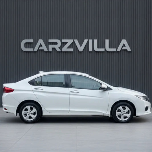 White car parked in front of a gray wall with 'CARZVILLA' branding.