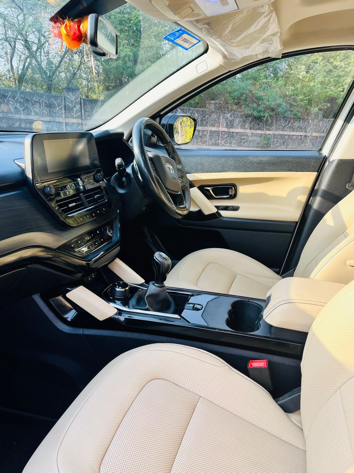 Car interior with beige seats and dashboard, showing steering wheel and gear shift.