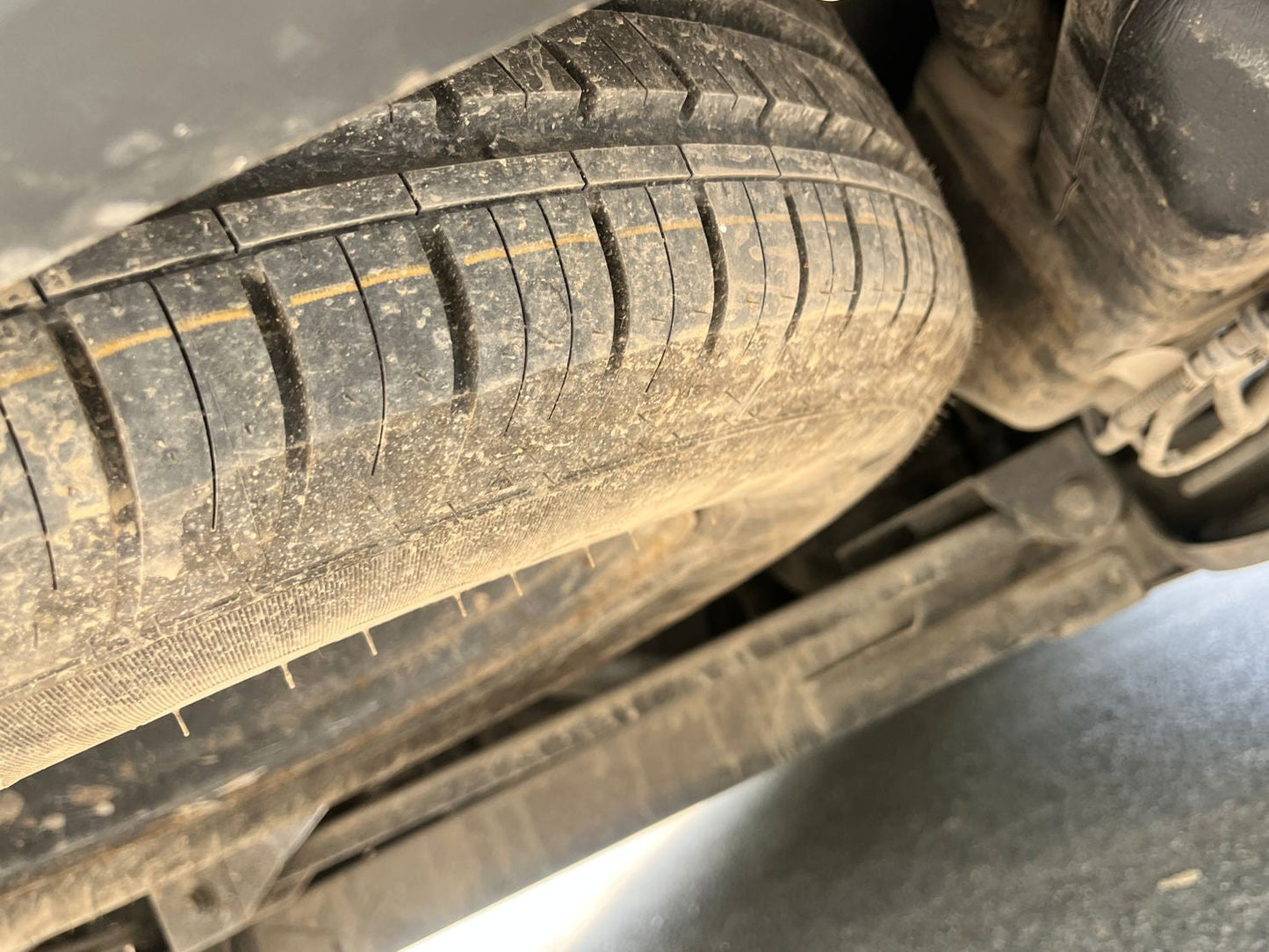 Close-up of a car tire with visible tread pattern and suspension components.