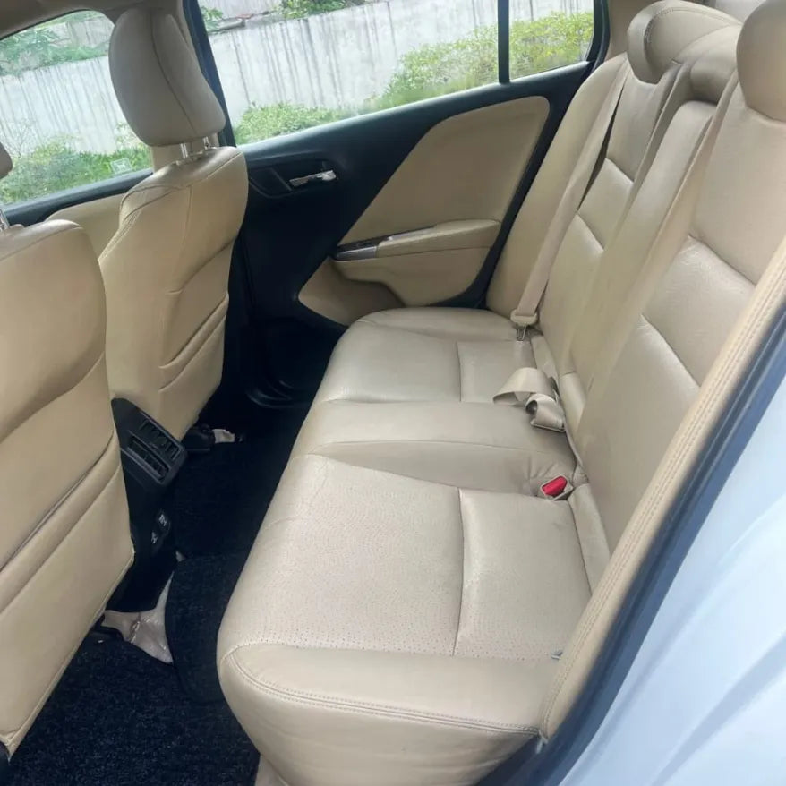 Beige car interior with visible seat belts and door handles.