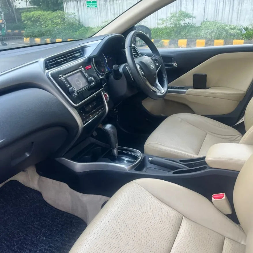 Car interior with beige seats and dashboard, showing steering wheel and controls.