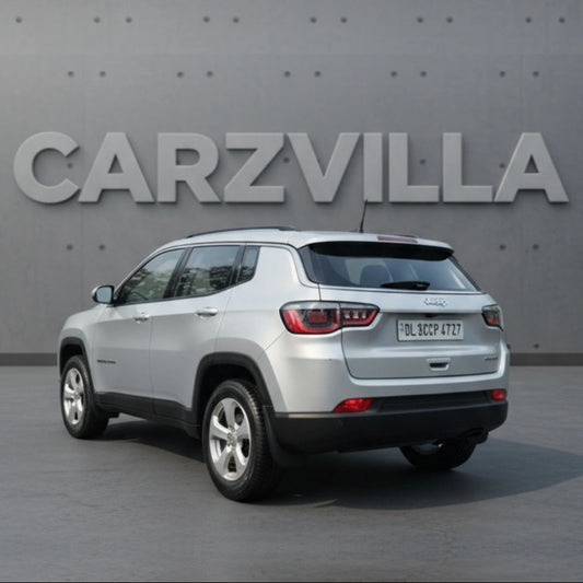 White SUV parked in front of a gray wall with 'CARZVILLA' branding.