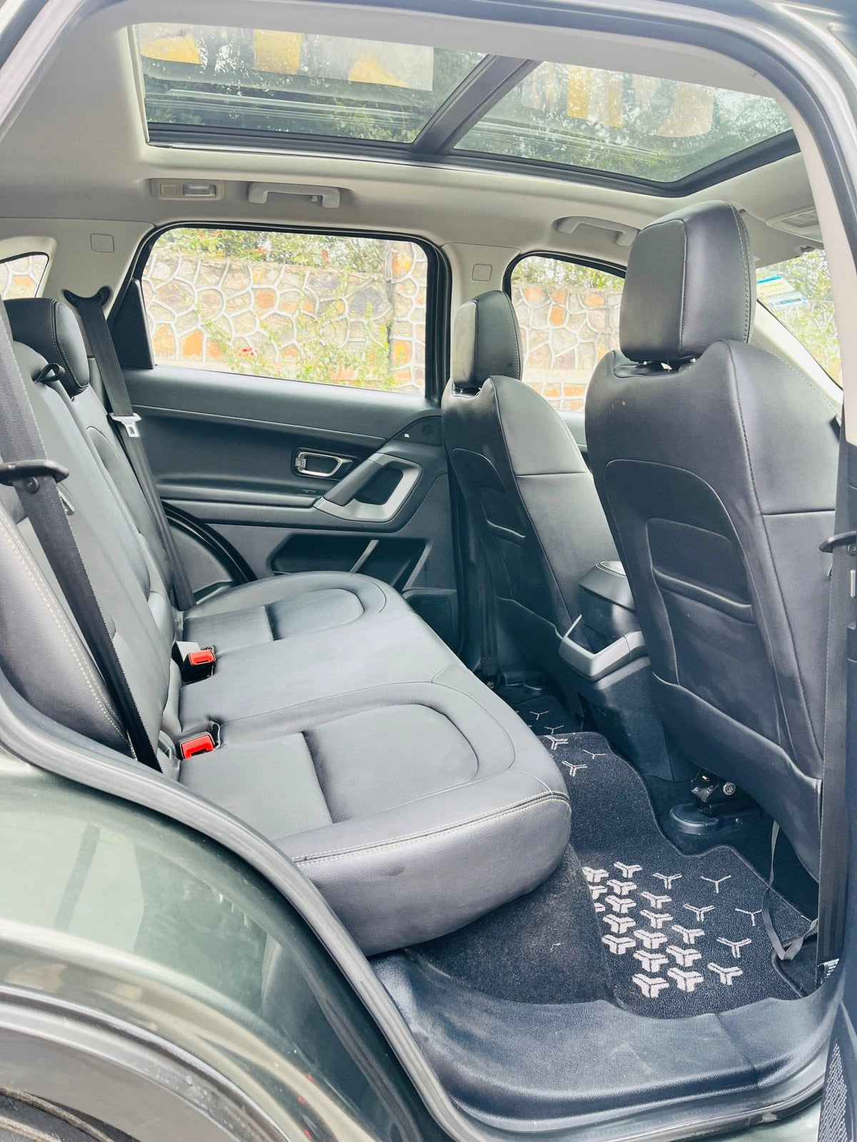 Back seat of a car with gray seats and a sunroof, showing a blurred outdoor scene through the windows.