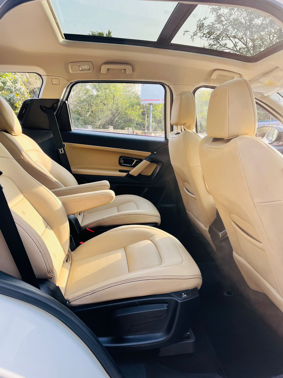 Beige interior of a car with sunroof and visible exterior through windows