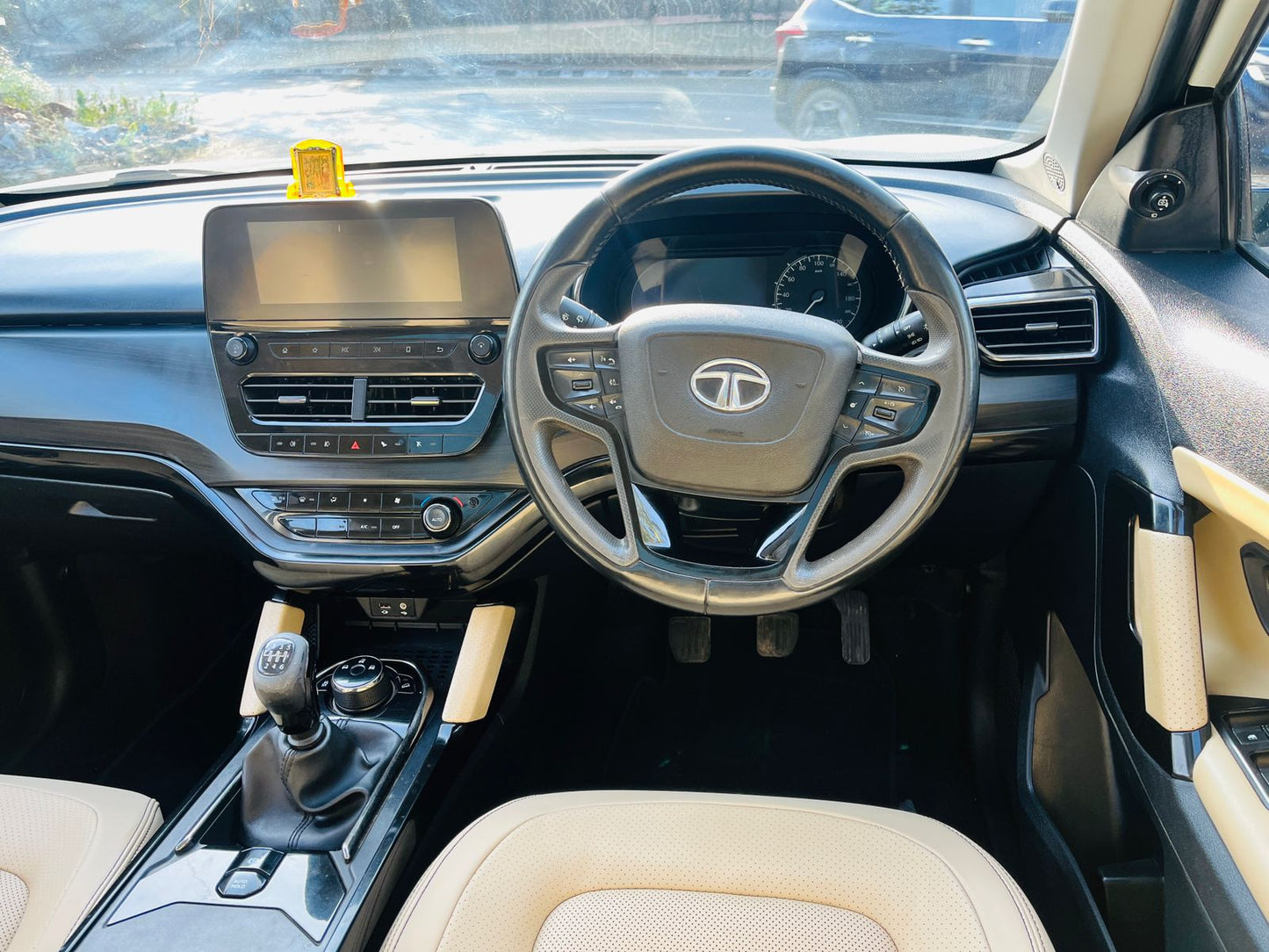 Car interior with steering wheel and dashboard, featuring a Tata logo.