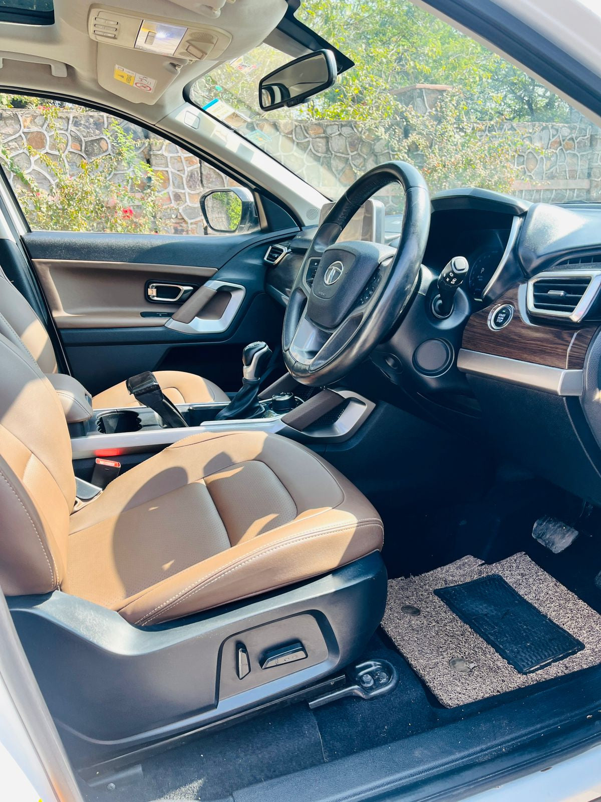 Car interior with beige seats and a view of the outdoors through the windows.
