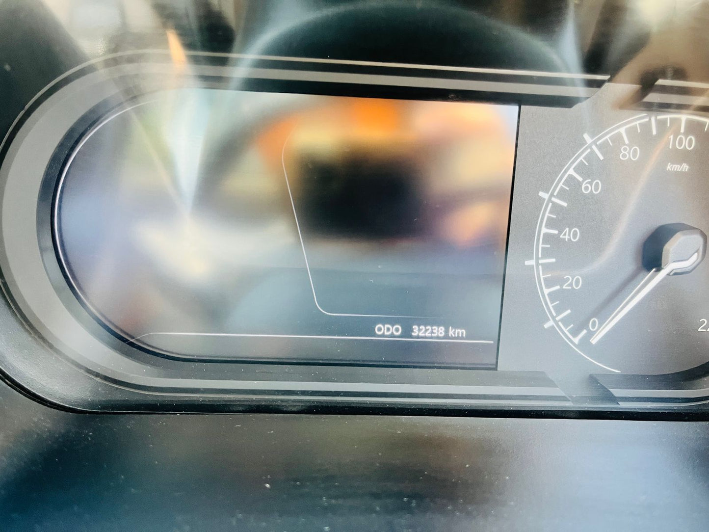 Car dashboard with digital display and speedometer, blurred background