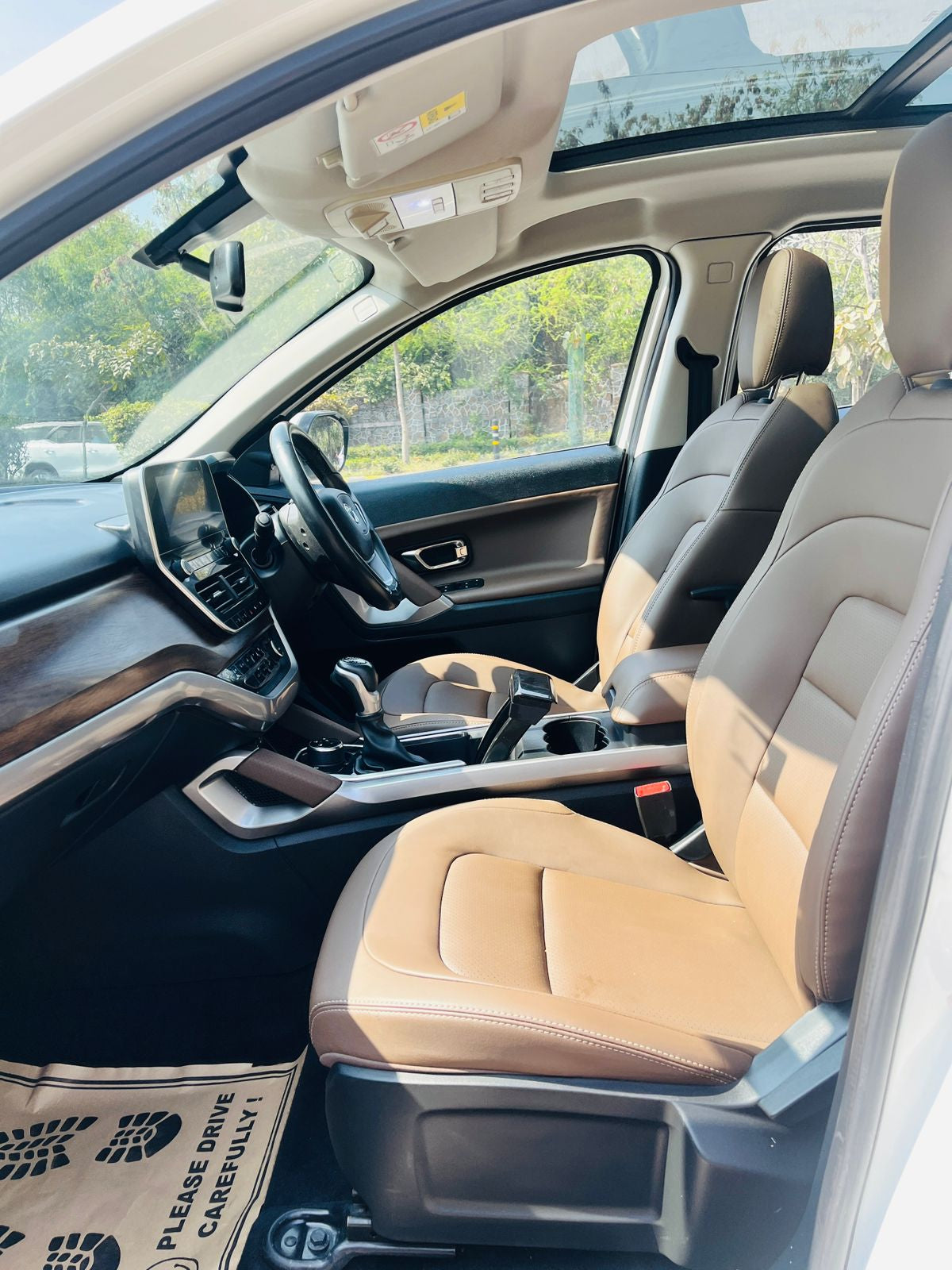 Car interior with beige seats and dashboard, showing a clear view of the road.