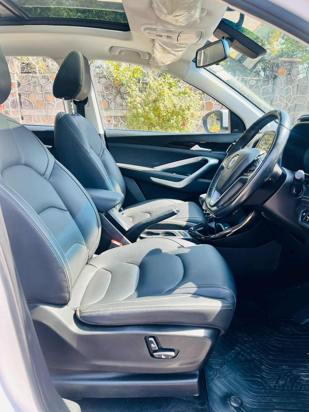 Car interior with gray seats and steering wheel, visible through a window.