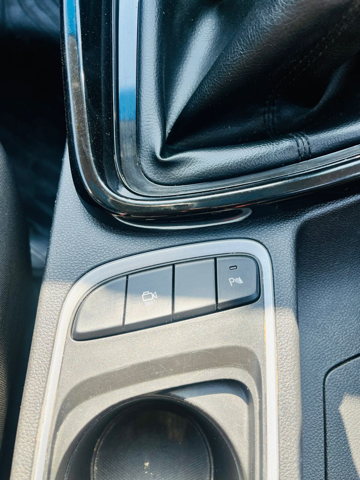 Close-up of a car's center console with cup holder and control buttons.