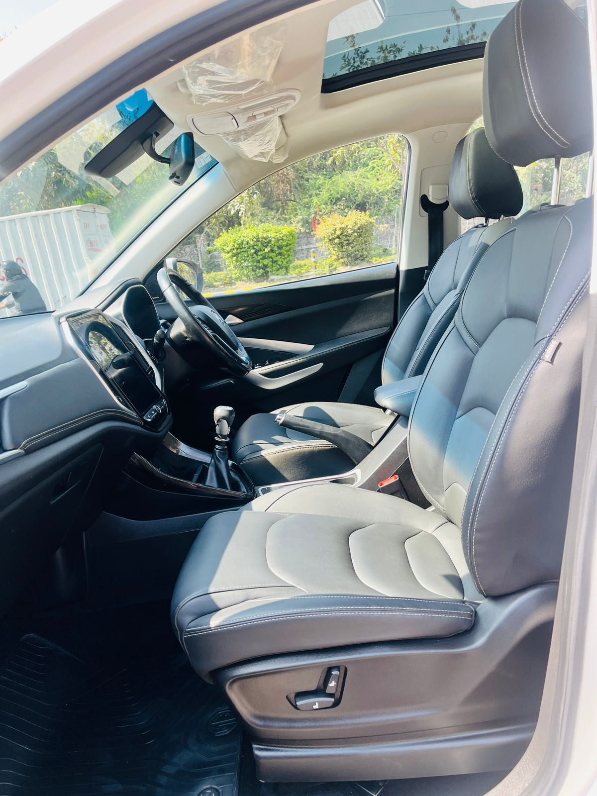 Car interior with gray seats and dashboard, showing a clear view of the steering wheel and door panels.