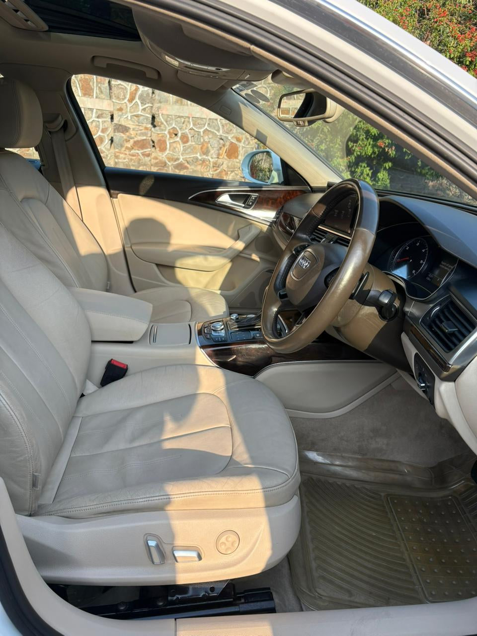 Car interior with beige seats and dashboard, sun shining through the windows.