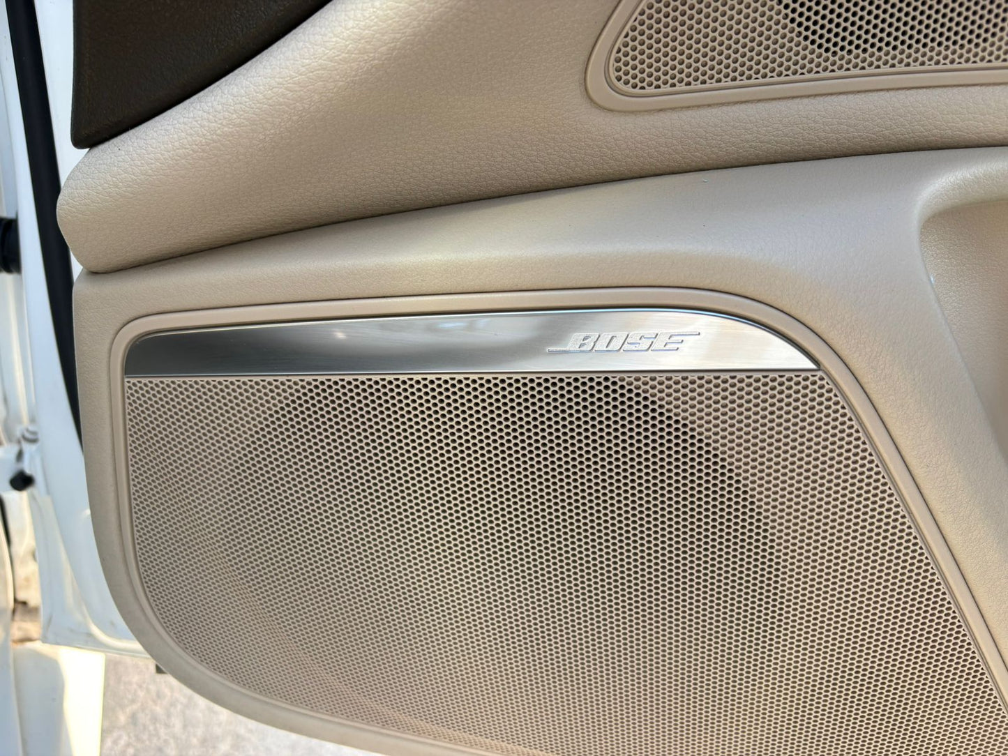 Car interior speaker with 'Harman Kardon' branding on a beige dashboard.