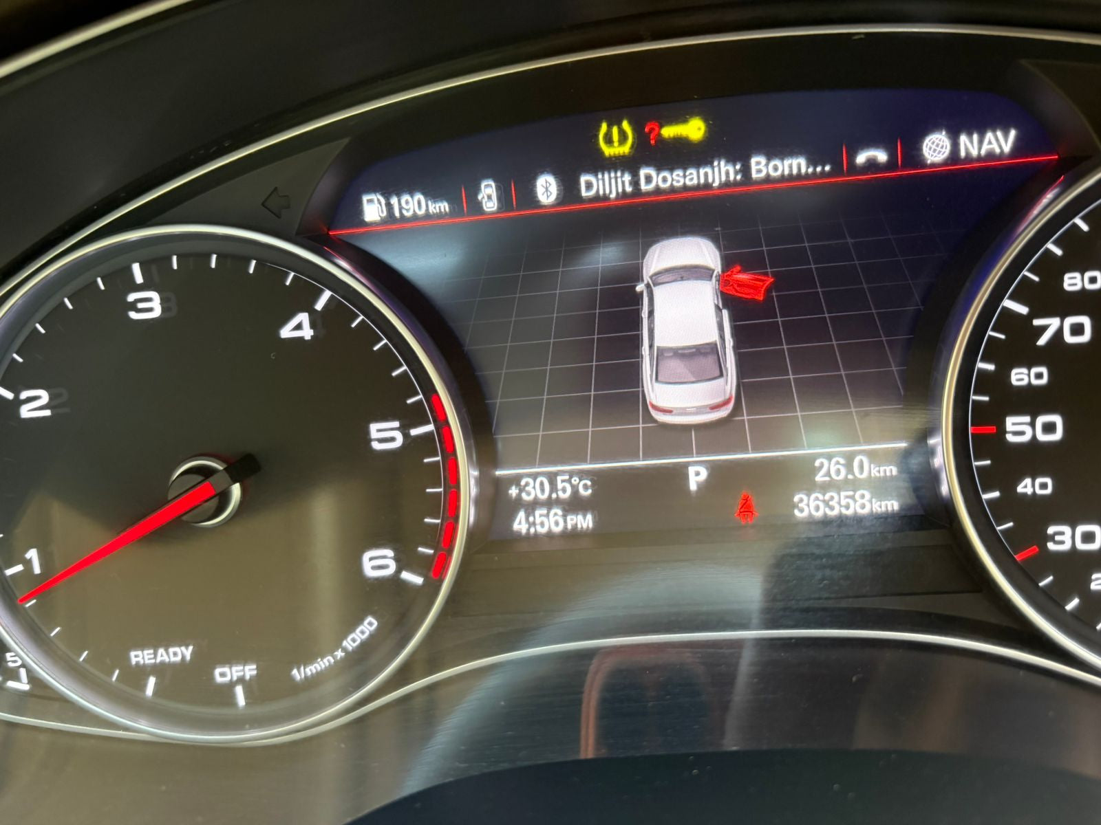 Car dashboard with digital display showing navigation and vehicle status indicators.