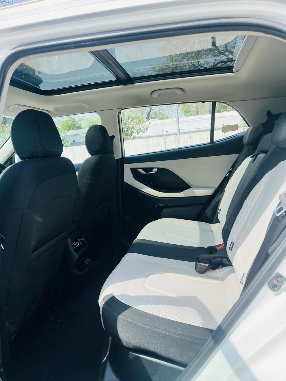 Back seat of a car with sunroof and visible exterior through windows