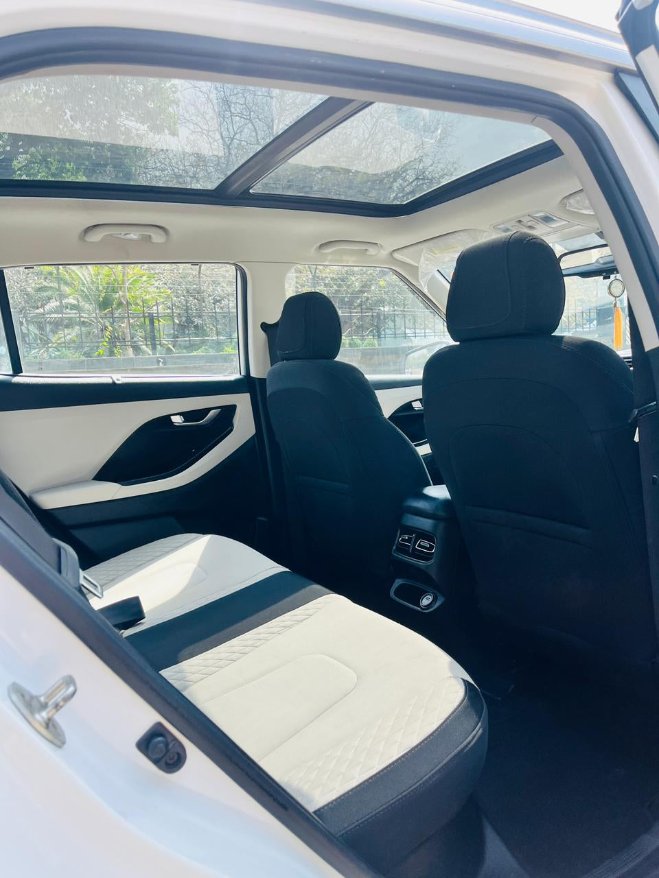 Car interior with black seats and a sunroof, showing a blurred outdoor background.