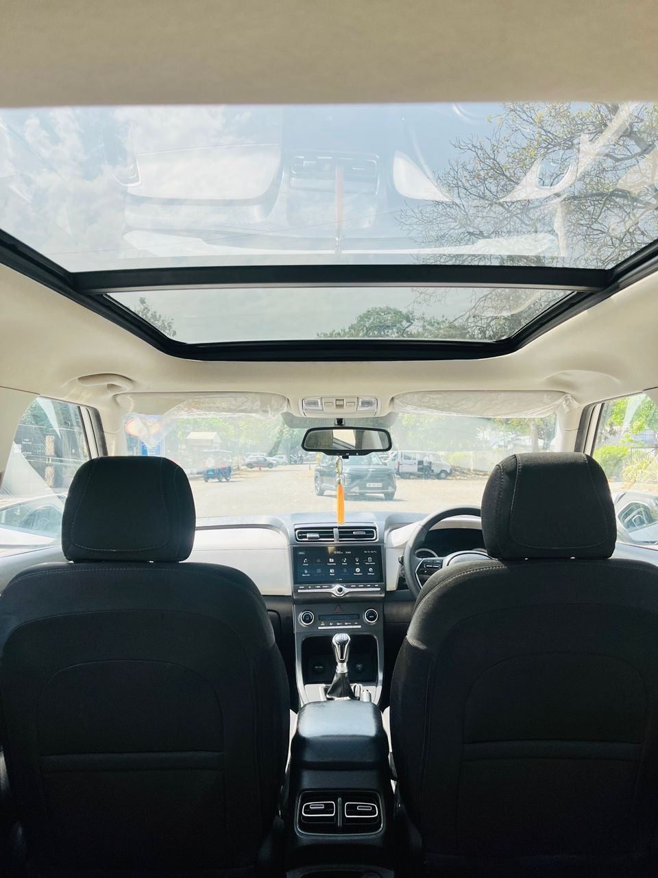 Car interior with a panoramic sunroof showing a clear sky.