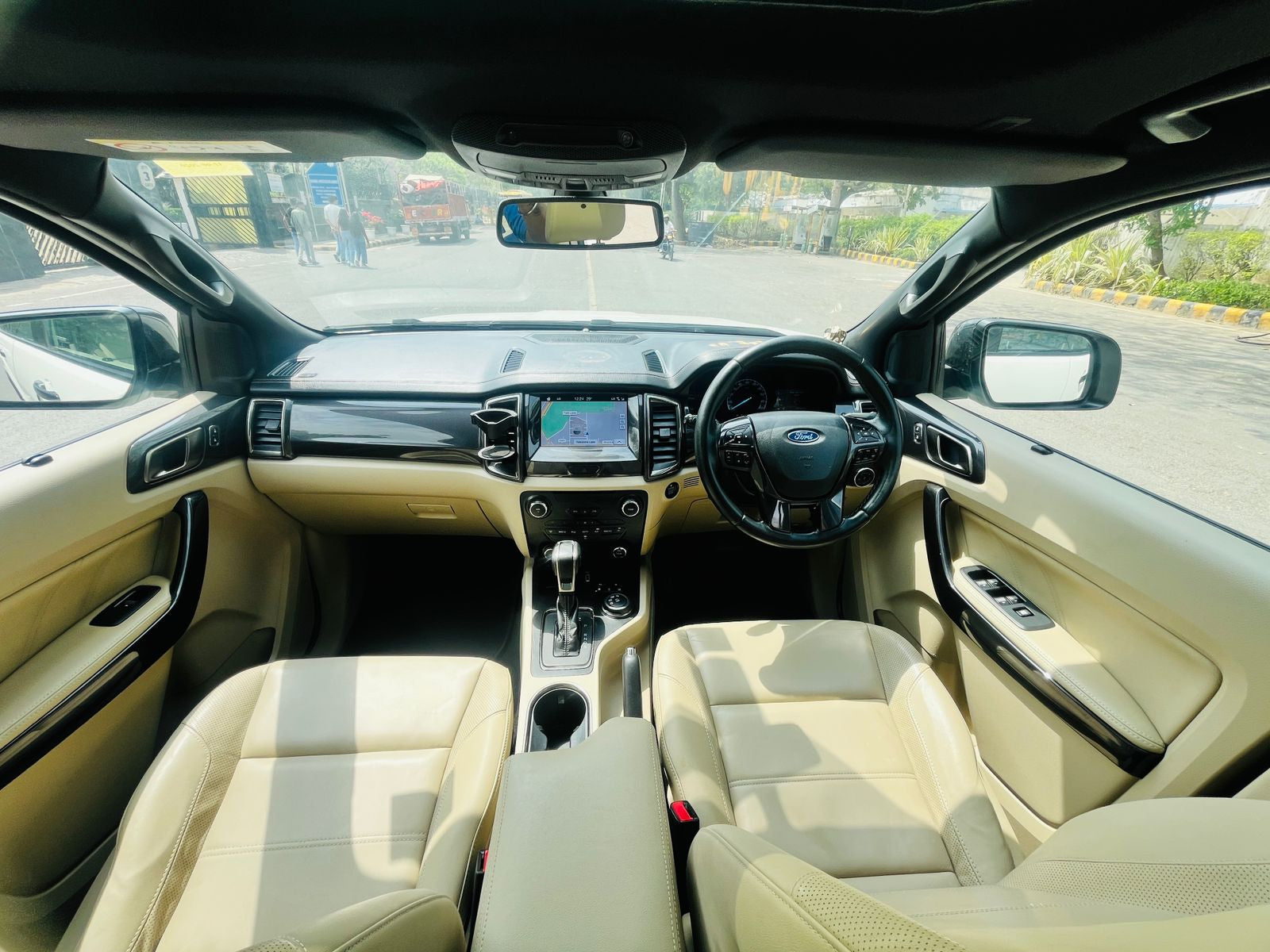 Car interior with beige seats and dashboard, showing a road through the windshield.
