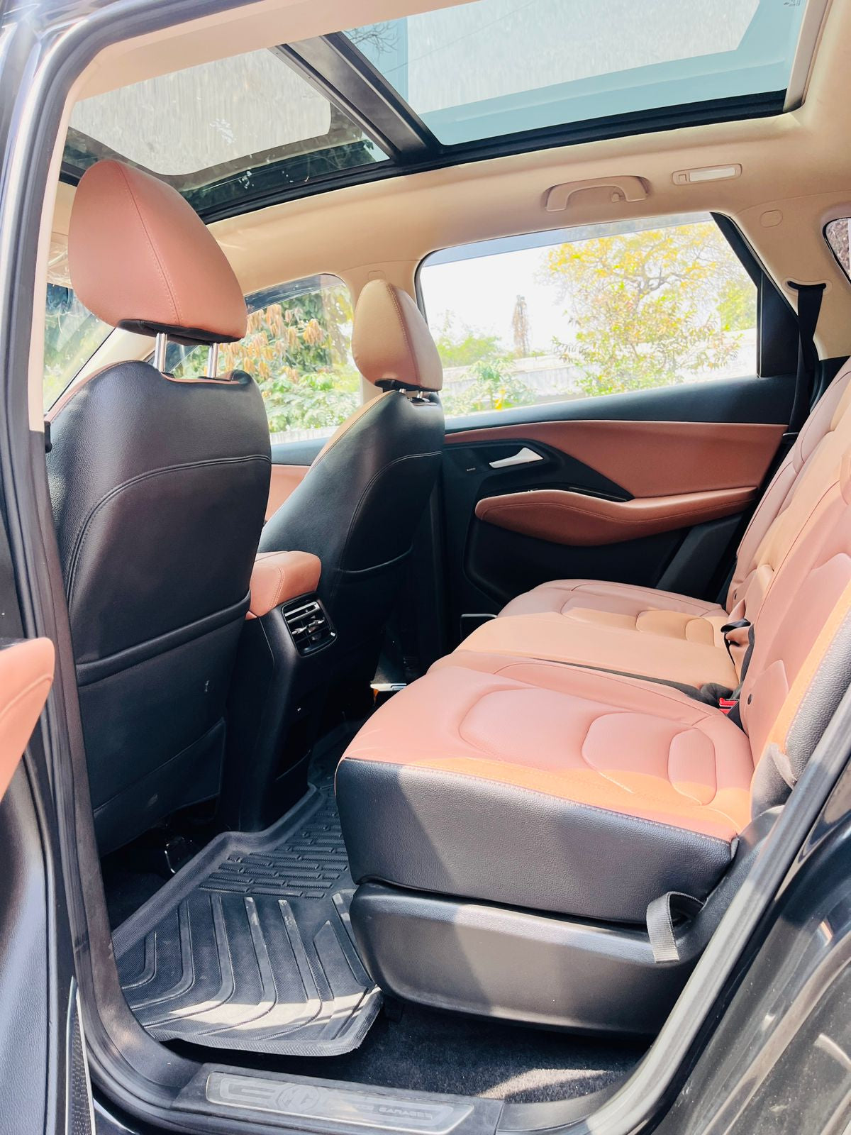 Car interior with brown leather seats and a sunroof.