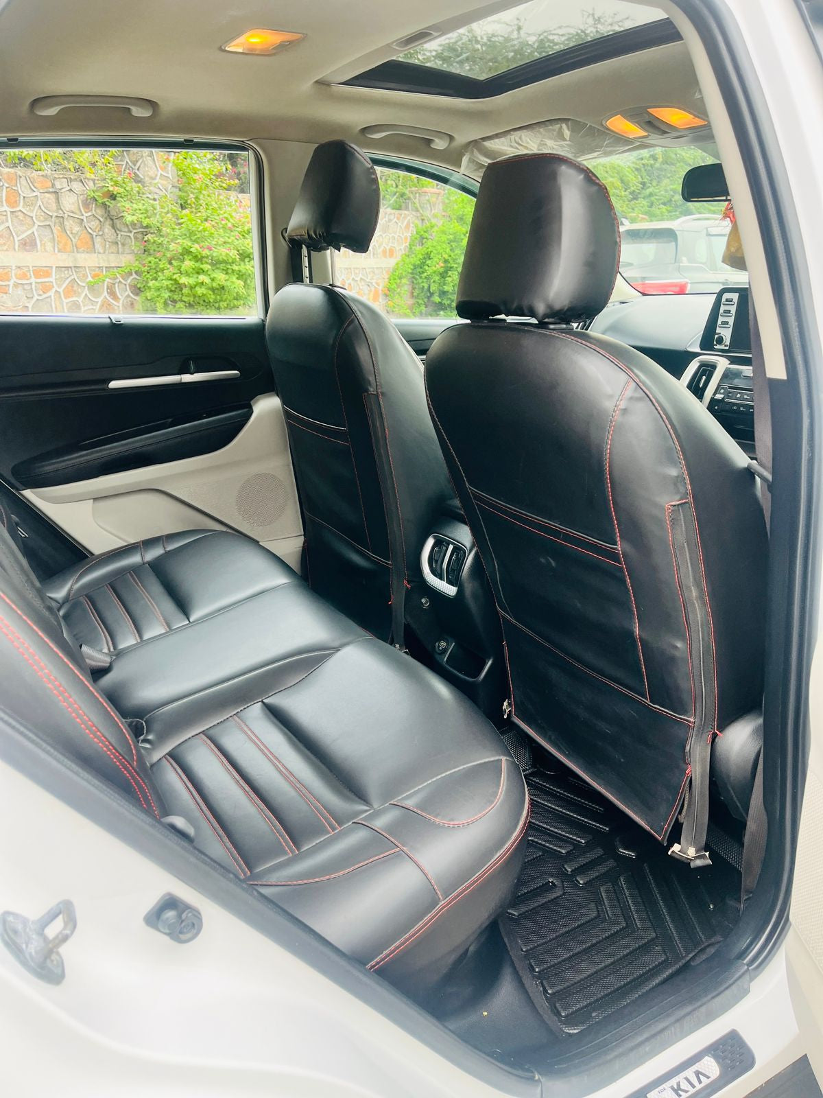 Car interior with black leather seats and red stitching.