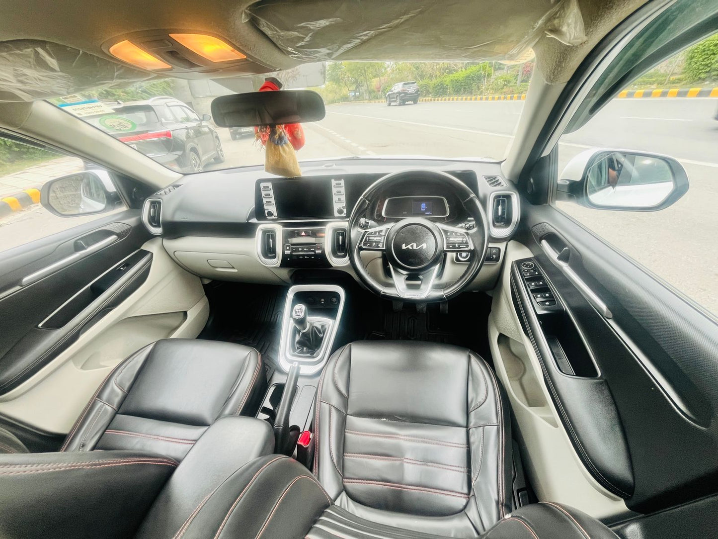 Car interior with dashboard and steering wheel visible, showing a road scene outside.