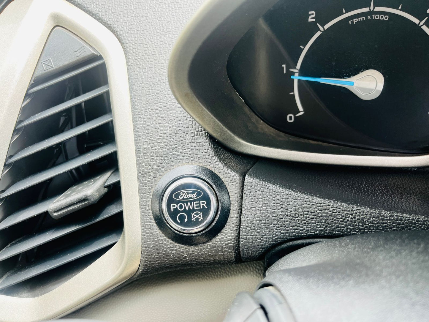 Car dashboard with Ford power button and tachometer
