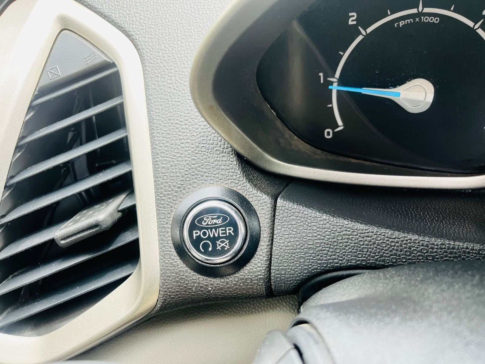 Car dashboard with Ford power button and tachometer