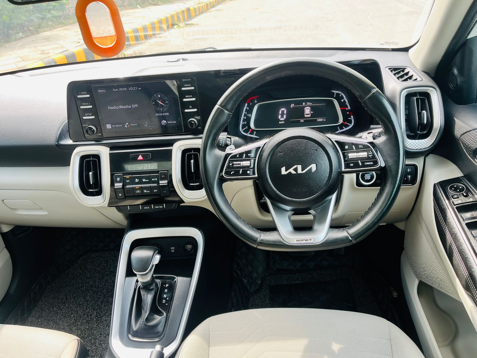 Car interior with steering wheel and dashboard featuring a Kia logo.