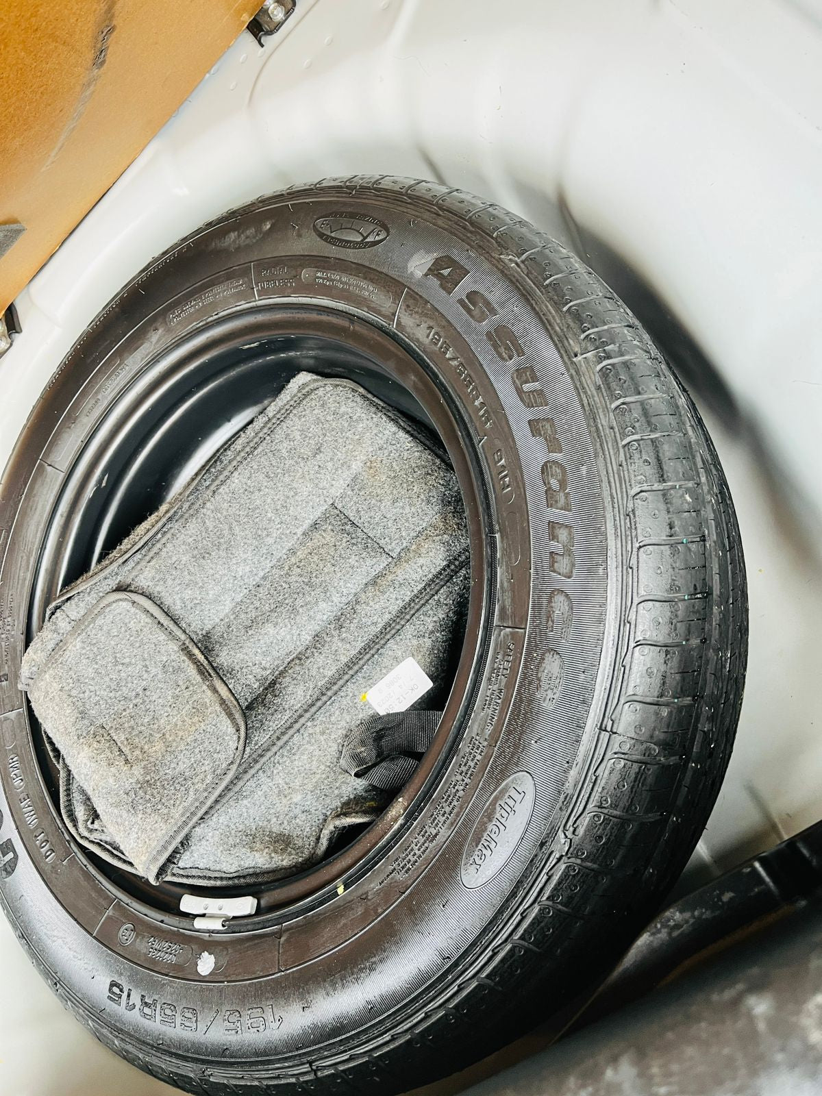 Car tire with a spare tire inside a white container, possibly for storage or transportation.
