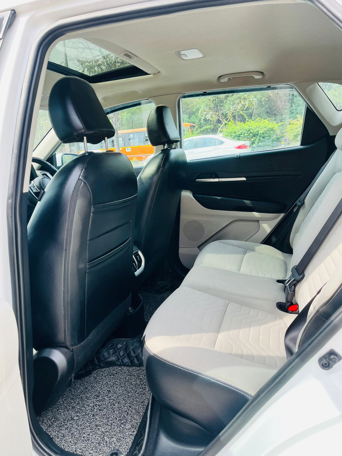 Car interior with black and beige seats, visible through a car window.
