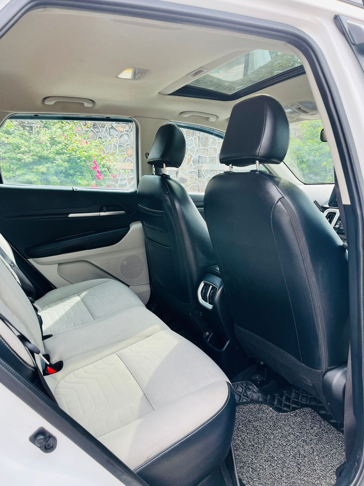 Backseat of a car with white and black seats, showing the interior design.