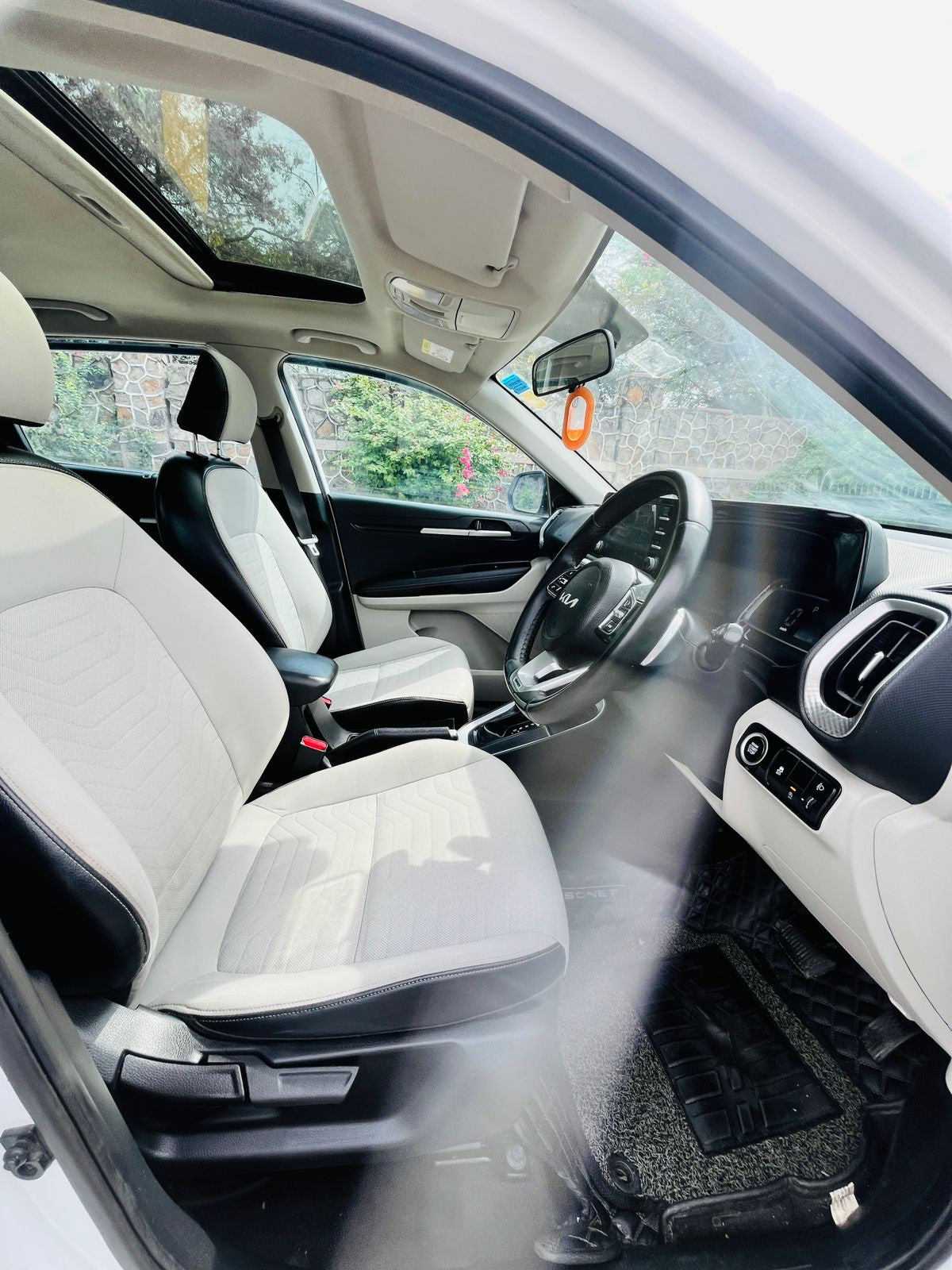 Car interior with a view of the dashboard and steering wheel, showing a freshener hanging from the rearview mirror.