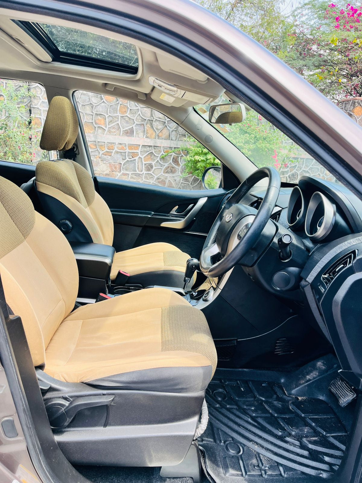 Car interior with beige seat covers and a steering wheel.