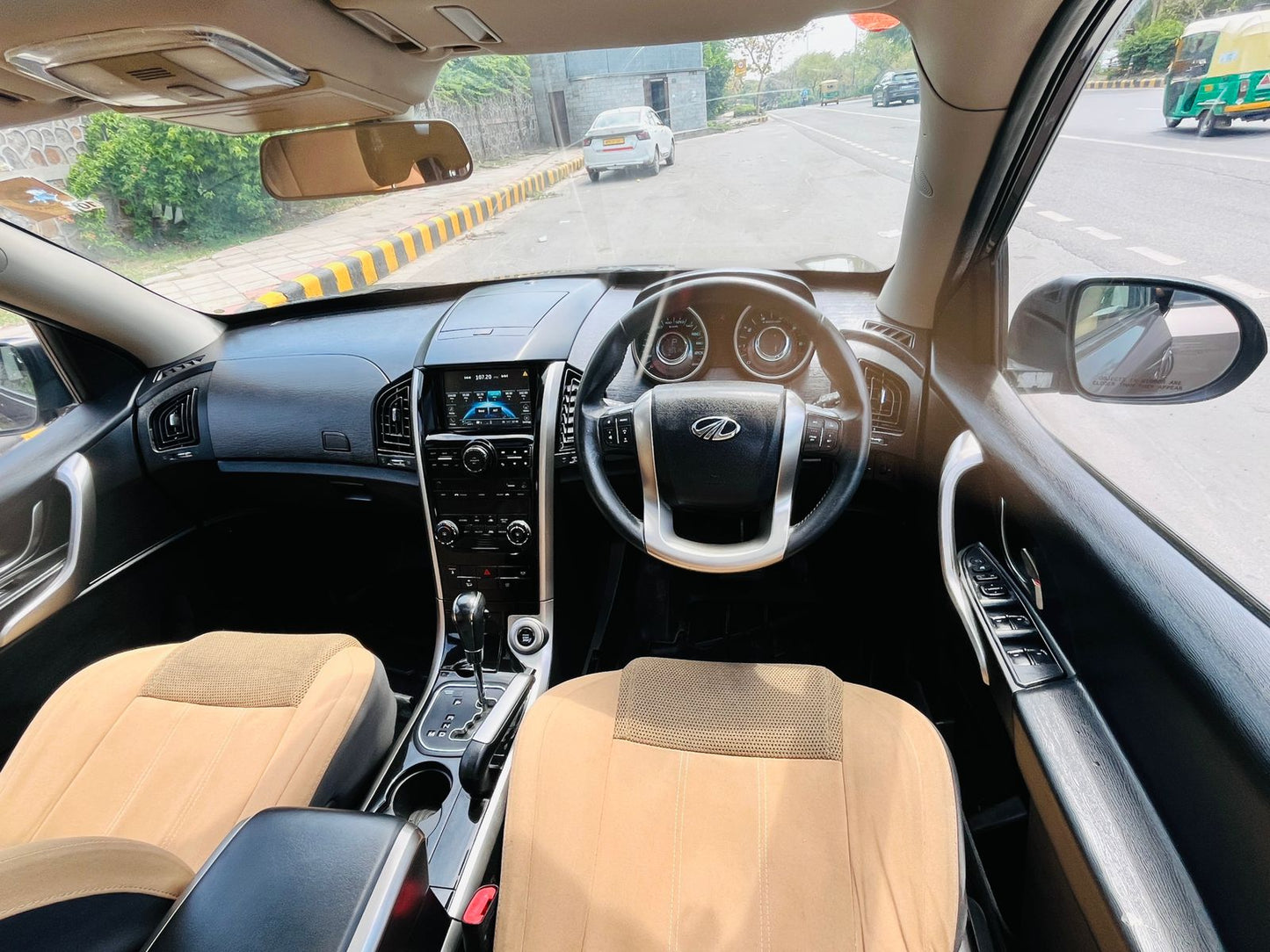 Car interior with beige seats and dashboard, road visible through windshield.