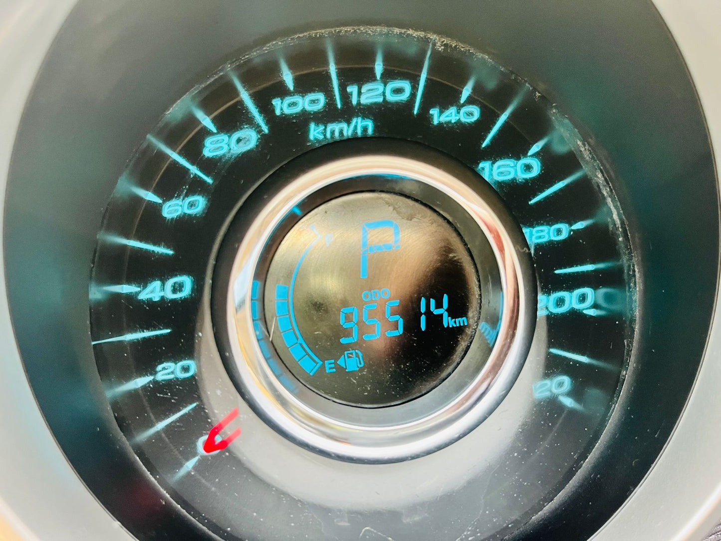 Close-up of a car dashboard with a speedometer and digital display showing various metrics.