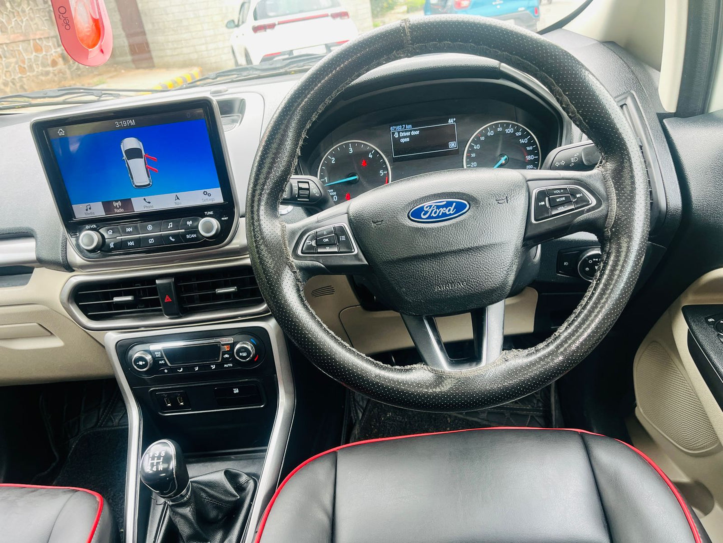 Car interior with steering wheel and dashboard, featuring a Ford logo.