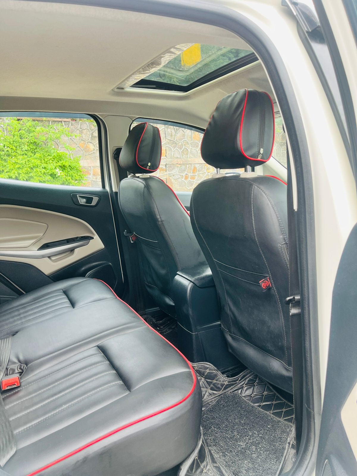 Car interior with black and red seat design, showing a clear view of the backseat and door panel.