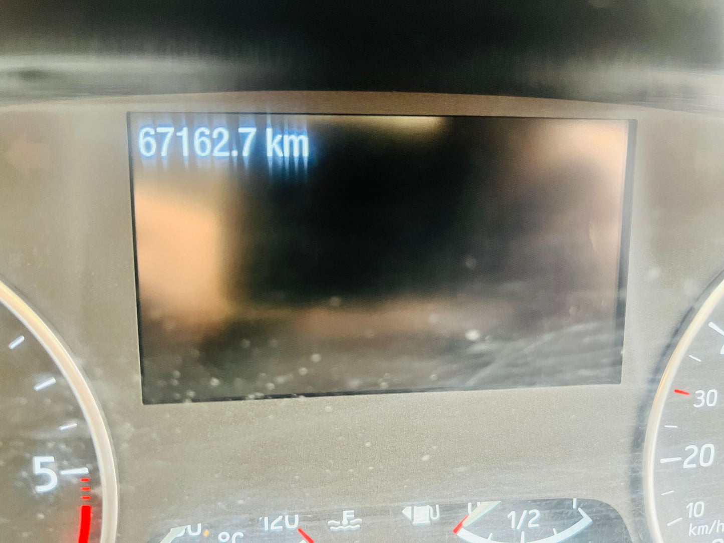 Car dashboard with digital display showing 67162.7 km.