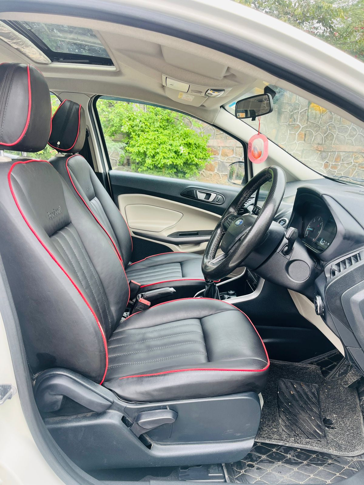 Car interior with black leather seats and red stitching, steering wheel, and dashboard.