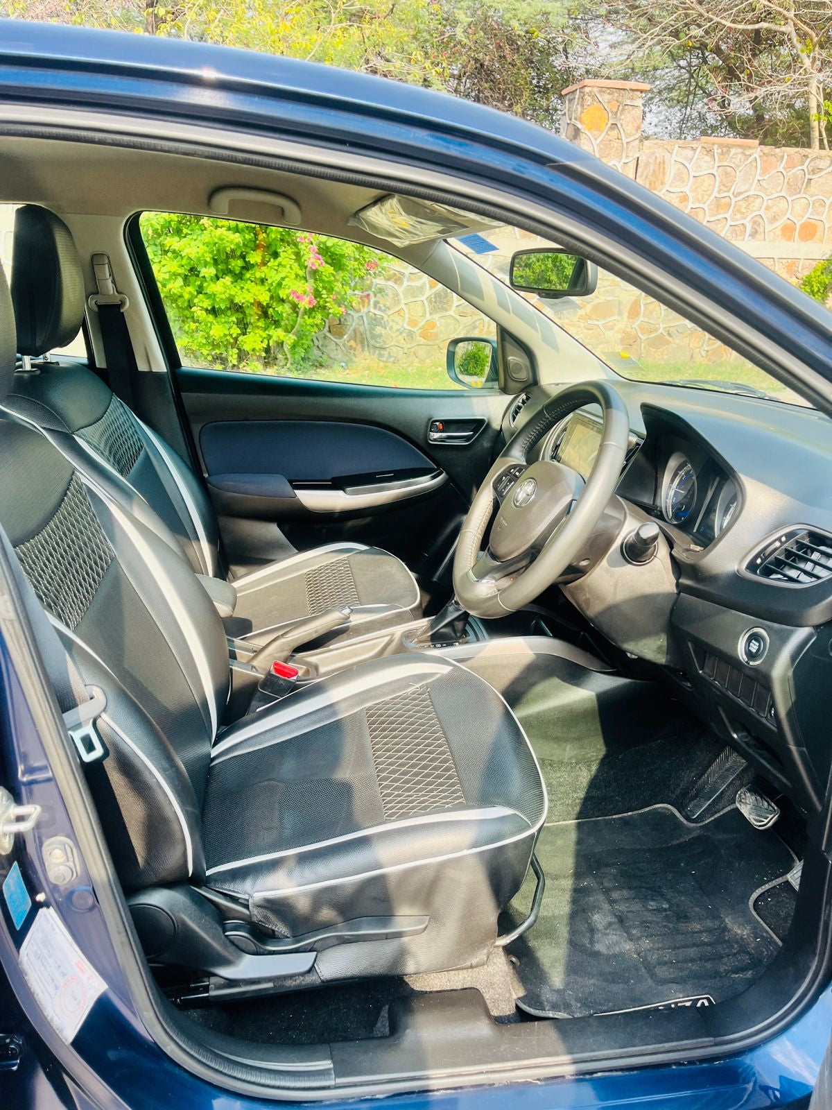 Car interior with open door, showing dashboard and steering wheel.