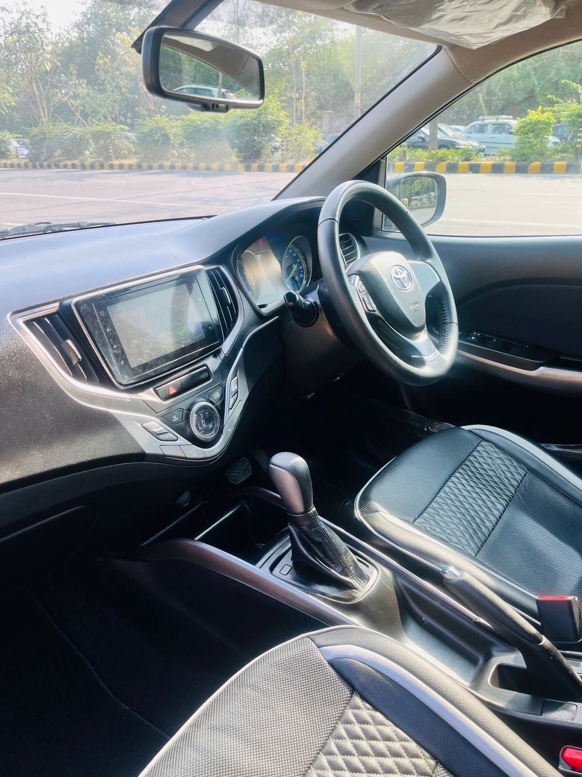 Car interior with dashboard, steering wheel, and gear shift in a vehicle.