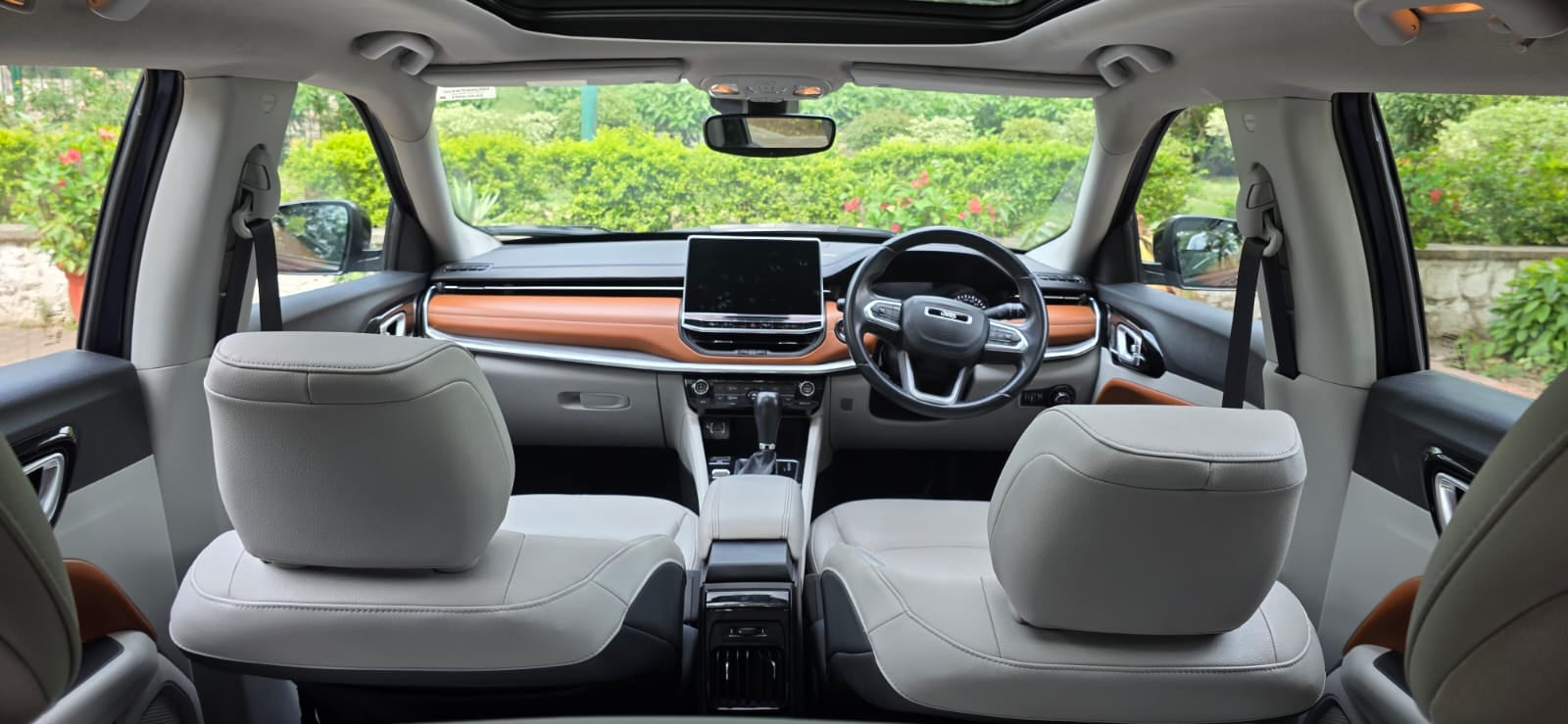 Interior of a modern car with white seats and a dashboard view.