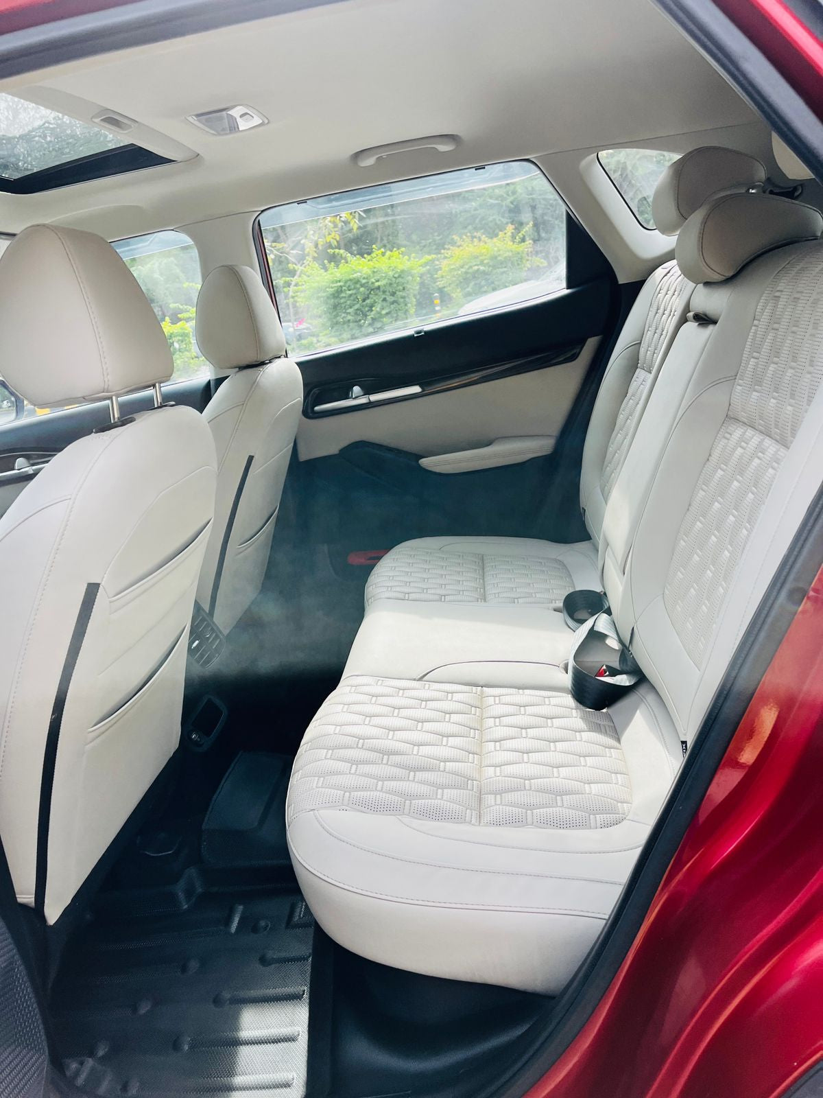 Backseat of a car with white leather seats and a red exterior.