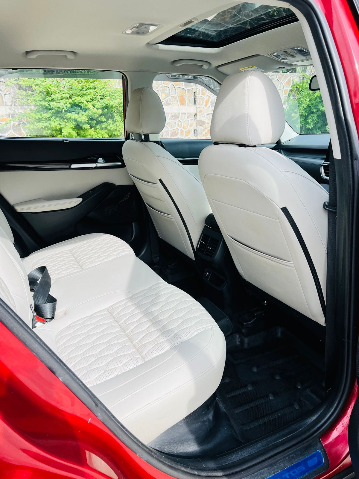 Back seat of a car with white leather seats and a red exterior.