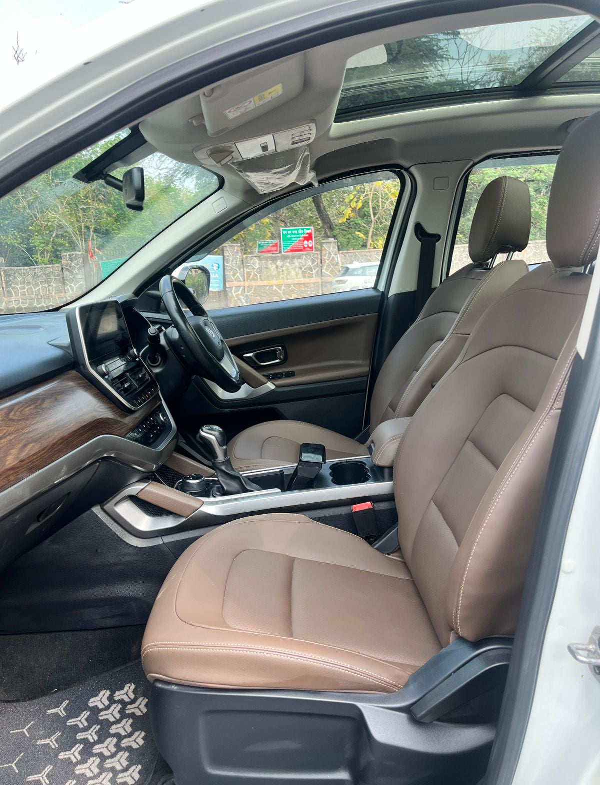 Car interior with beige seats and dashboard, showing steering wheel and controls.