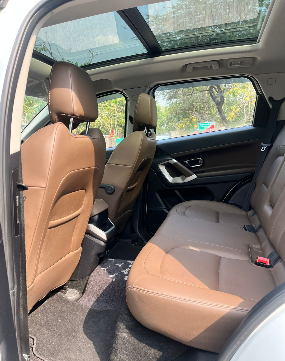 Beige interior of a car with sunroof and visible windows showing outdoor scenery.