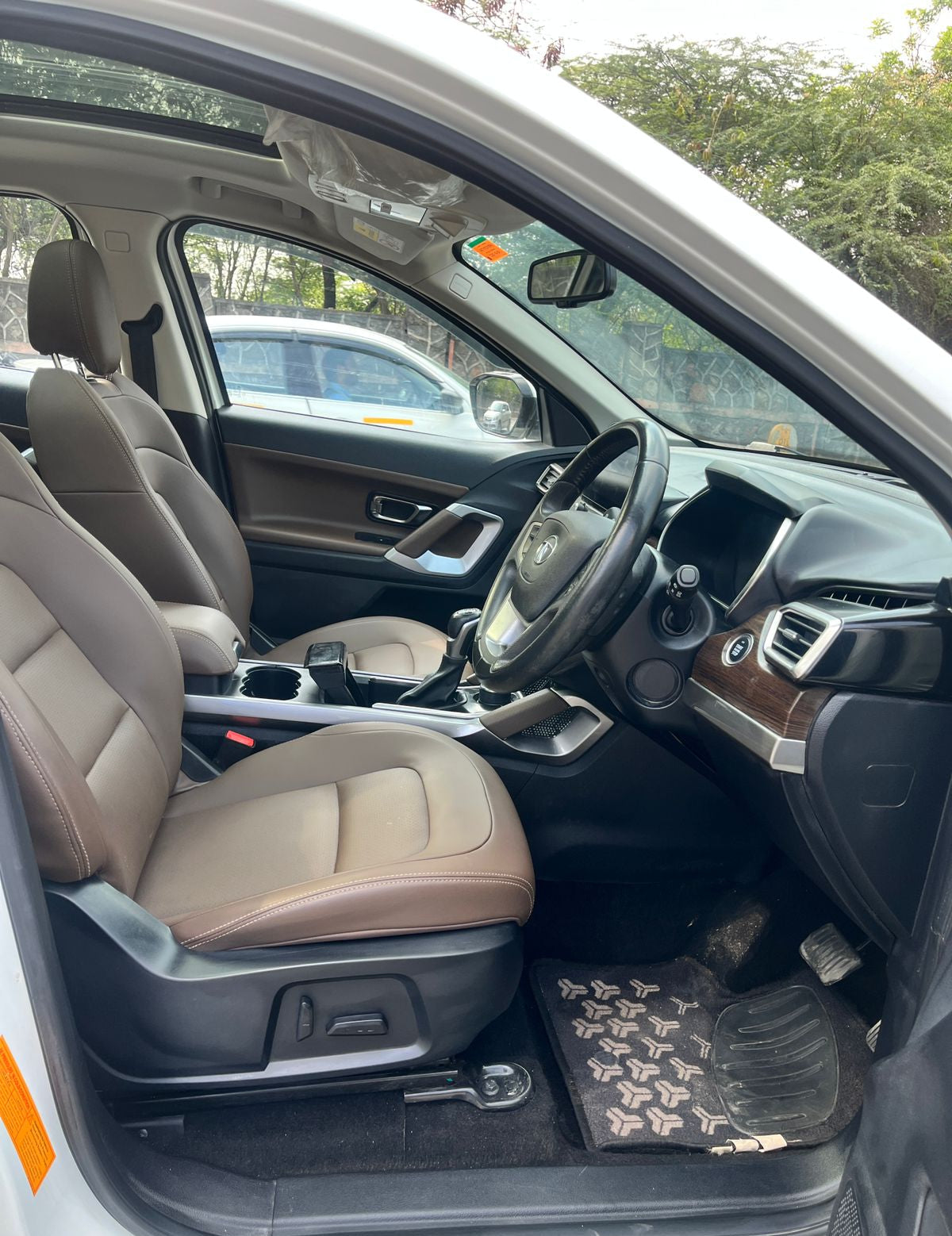 Car interior with beige seats and a steering wheel, showing dashboard and door panels.