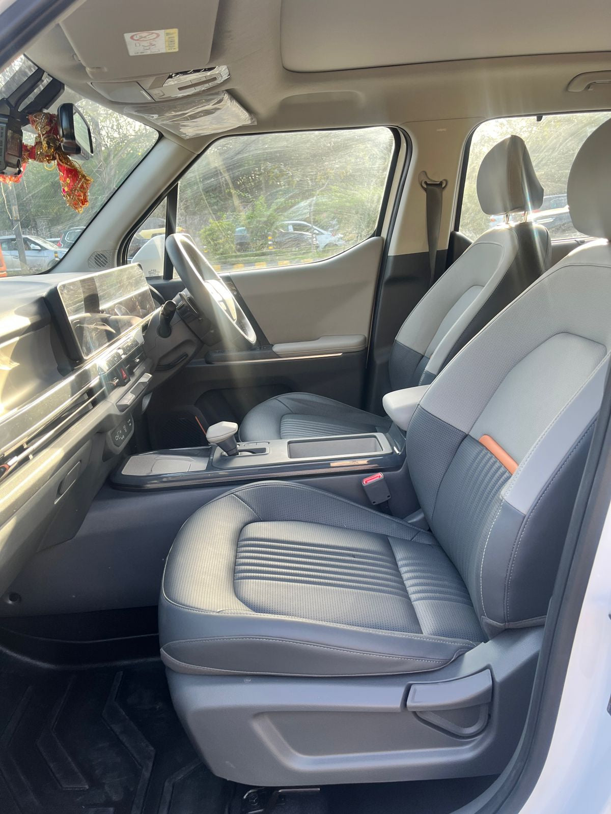 Car interior with gray seats and dashboard, showing a clear view of the steering wheel and door panels.