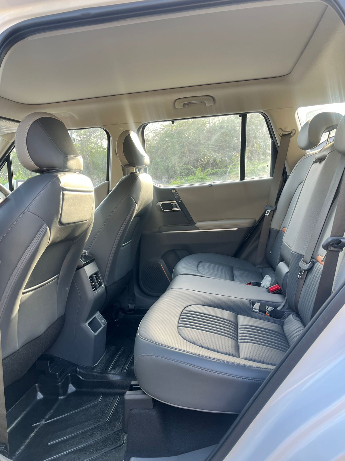 Backseat view of a car interior with gray seats and visible windows.