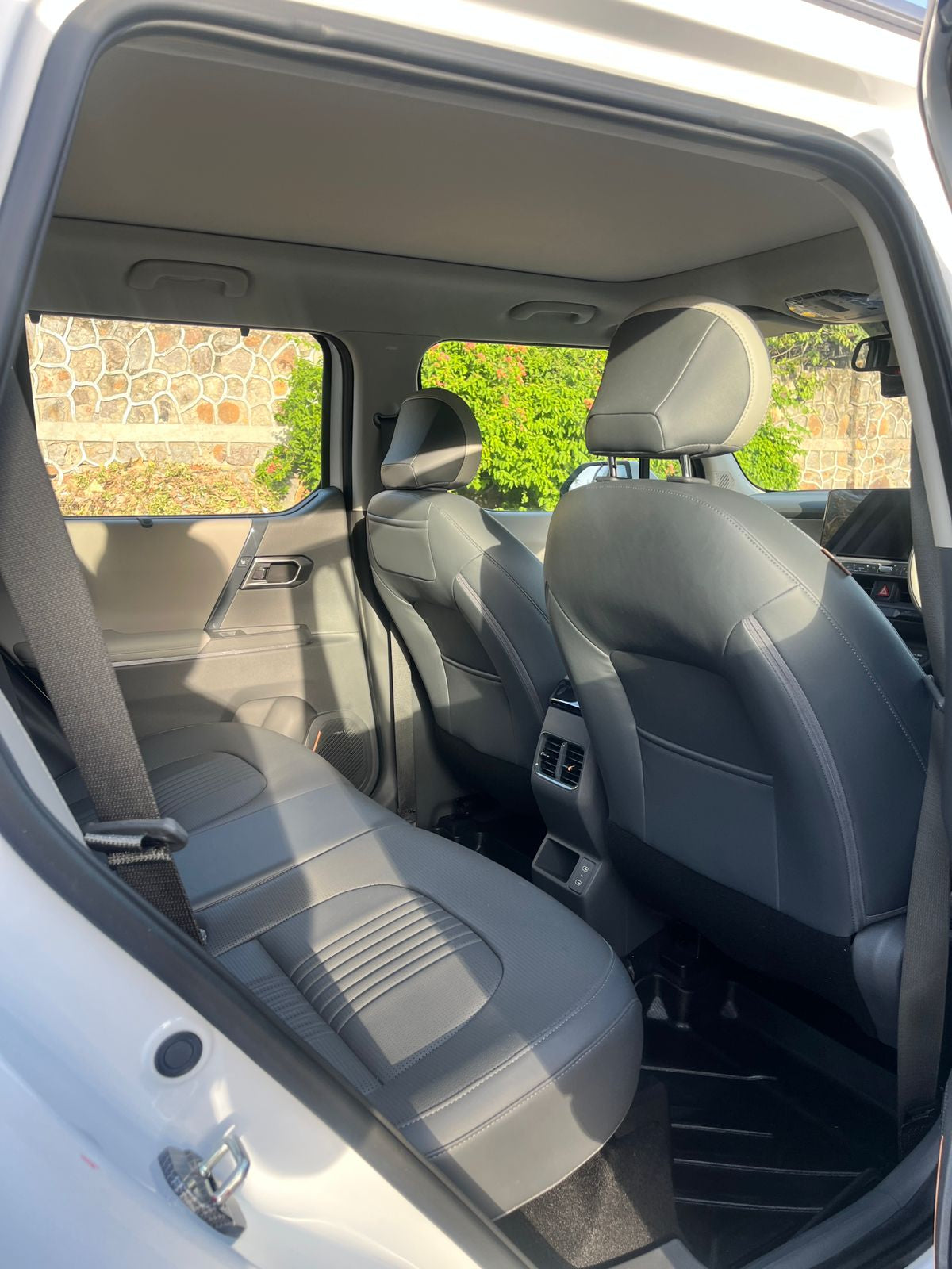 Interior of a car with gray seats and a view of greenery outside